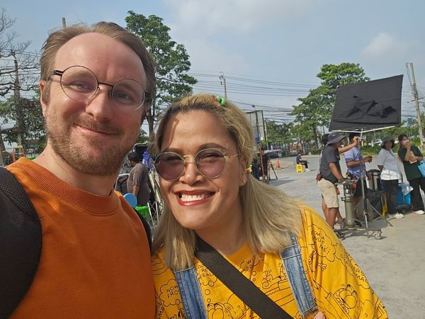 Robin Schroeter coaching a model for an ad on a Bangkok set, emphasizing expertise.